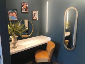 a bathroom with a sink and two mirrors and a chair at Waterfront Southport Hotel in Southport