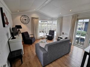 a living room with a gray couch and chairs at Giet Oan gelegen op Resort Venetië in Giethoorn