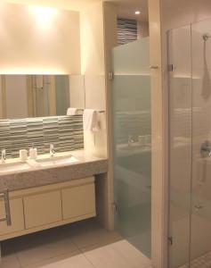 Un baño con ducha de cristal y lavabo. en The Emperor, en Johannesburgo