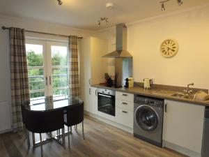 a kitchen with a washer and a sink and a table at Luxury Riverbank Apartment, Nairn in Nairn