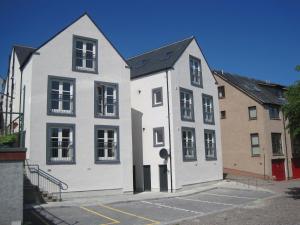 a white building with black windows in a parking lot at Luxury Riverbank Apartment, Nairn in Nairn