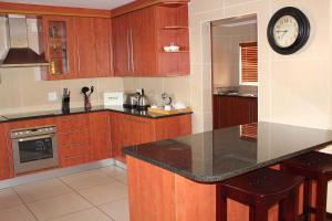una cocina con armarios de madera y un reloj en la pared en Topaz Cove Luxury Villas, en Edenvale