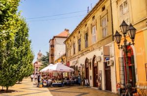 a street with tables and an umbrella and buildings at Stan na dan Apartman Stella in Sombor