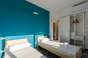 - 2 lits dans une chambre avec un mur bleu dans l'établissement JOIVY Spacious Apt for 6, Near Train Station and Beach, à Sestri Levante