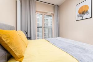 a bedroom with a yellow bed and a window at BG Premium Apartments Mennica Residence in Warsaw