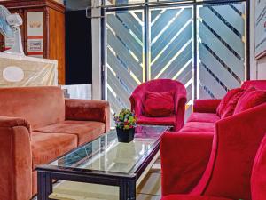 a living room with red chairs and a glass table at Penginapan Marsya Prima Syariah in Jakarta