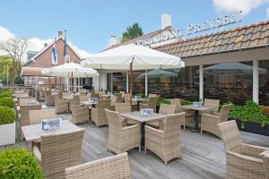 een patio met tafels, stoelen en parasols bij Fletcher Hotel Restaurant Prinsen in Vlijmen