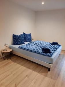 a bedroom with a bed with blue pillows and a table at Mill D'Arx in Château