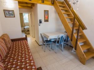 Una sala de estar con una mesa y una escalera. en Departamentos De la Plaza, en Villa La Angostura