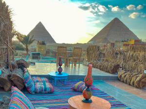 un gruppo di vasi seduti su un tappeto di fronte alle piramidi di Atlantis pyramids inn a Il Cairo