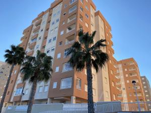 un edificio alto con palmeras delante en Luz Bahía, en La Manga del Mar Menor