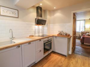uma cozinha com armários brancos e um lavatório em Chapel Cottage em Corbridge