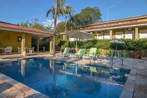 a swimming pool with chairs and an umbrella next to a house at Villa do Conde in Brotas