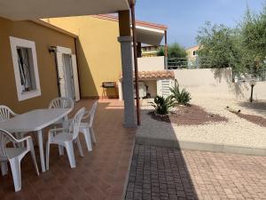 eine Terrasse mit einem Tisch und Stühlen sowie ein Haus in der Unterkunft Villa Girasole in Valledoria