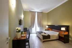 Hotel Ambasciatori في باليرمو: غرفة نوم بسرير ومكتب ونافذة