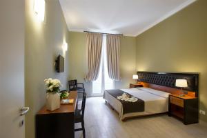 a bedroom with a bed and a desk and a window at Hotel Ambasciatori in Palermo