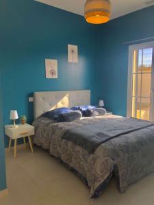1 dormitorio con 1 cama grande y pared azul en La Maison de Laurie en Pézenas