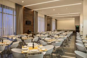 a dining room with tables and white chairs at Fiesta Inn Chihuahua Fashion Mall in Chihuahua