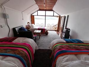 um quarto com duas camas e uma sala de estar em Uros Lake Titicaca Lodge em Puno