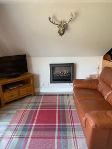 a living room with a couch and a fireplace at Hayfield lodge in Spean Bridge