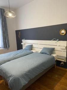 a bedroom with two beds with a headboard and a mirror at le coeur de ville in Dinant