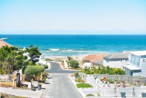a road leading to a beach with houses and the ocean at Kaalvoet Self-Catering Apartments in Yzerfontein