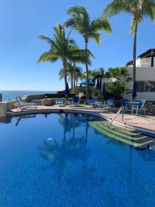 una gran piscina con palmeras y sillas en Ocean View Cabo Condo Create Memories!!, en San José del Cabo