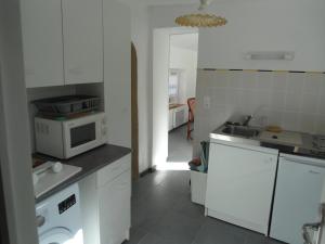 a white kitchen with a sink and a microwave at LA VUULE MAISON in Fermanville