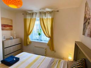 a bedroom with yellow curtains and a bed and a window at Grand Central Apartments in Derby