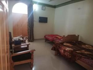 a room with two beds and a television in it at Riverside Hotel Kalam in Kārandūkai