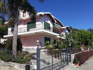 een roze huis met een hek en een palmboom bij Giardino Miramare CITRA zero zero ottanta trentuno LT 0737 in Imperia