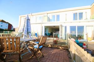 a patio with a table and chairs and a house at Serenity "your calm seafront retreat" By Air Premier in Seaford