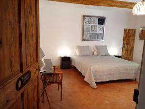 Schlafzimmer mit einem Bett und einem Tisch mit einem Laptop in der Unterkunft LE MAS DES FLANERAIES in Althen-des-Paluds