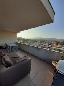 ein Wohnzimmer mit einem Sofa und einem Tisch auf dem Balkon in der Unterkunft Terrasse sur les Alpilles in Saint-Rémy-de-Provence