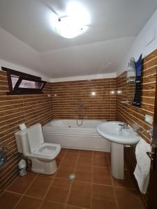 a bathroom with a tub and a toilet and a sink at Sofra Kolonjare Agroturizem in Ersekë