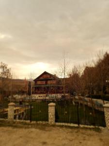 une grande maison avec une clôture devant elle dans l'établissement Sofra Kolonjare Agroturizem, à Ersekë