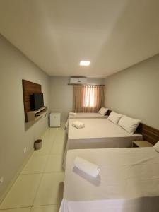 ボドケーナにあるHOTEL AGUAS DE BODOQUENAのベッド3台とテレビが備わるホテルルームです。