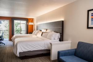 two beds in a room with a chair and a couch at Holiday Inn Express & Suites Custer-Mt Rushmore in Custer