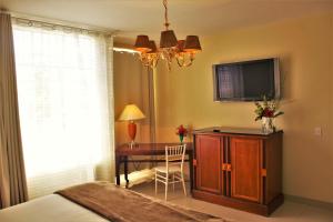 a bedroom with a bed and a desk with a television at Hotel del Angel in Guadalajara