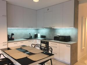 Apartament Fibra Grande في ريبنيك: مطبخ مع دواليب بيضاء وطاولة مع كراسي