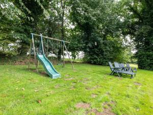 une aire de jeux avec un toboggan et deux chaises dans un champ dans l'établissement Charming child friendly holiday home, à La Boussac