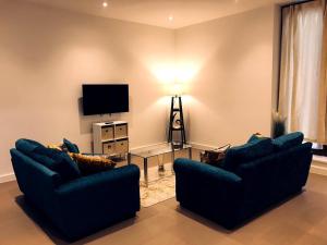 Sala de estar con 2 sofás azules y TV en Maplewood luxurious one-bed flat with free parking, en Saint Albans