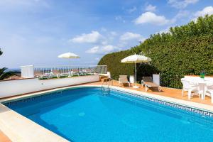 a swimming pool with a table and chairs and an umbrella at Villa Es Mirador in Son Bou