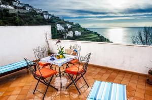 un tavolo e sedie su un balcone con vista sull'oceano di Tenuta Mamma Carmela ad Amalfi
