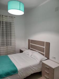 1 dormitorio con cama blanca y luz azul en Piso termal, en Ourense