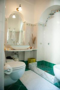 un bagno con un water, un lavandino e uno specchio di Tenuta Mamma Carmela ad Amalfi