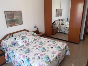 a bedroom with a bed with a floral comforter and a mirror at Anton Alvarez in Elche