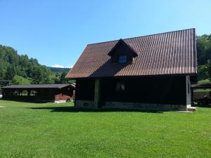 Czarna stodoła z czerwonym dachem na zielonym polu w obiekcie Chata Sipkova I w Tierchowej