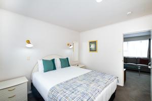 a white bedroom with a bed and a couch at Chevron Motel in Taupo