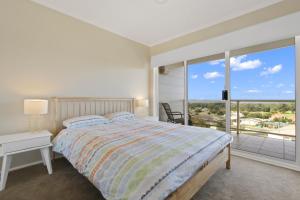 a white bedroom with a bed and a large window at Eastern Views Beach House - Spacious Family Escape in Lakes Entrance